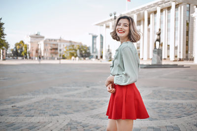 Portrait of smiling young woman standing in city