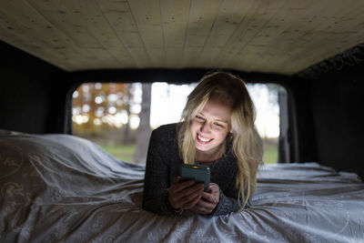 Young woman using phone while sitting on bed