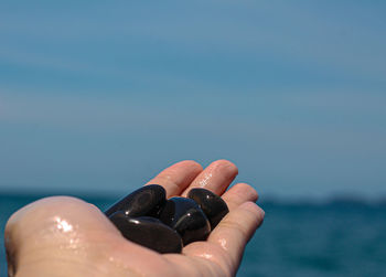 Close-up of hand holding sea against sky