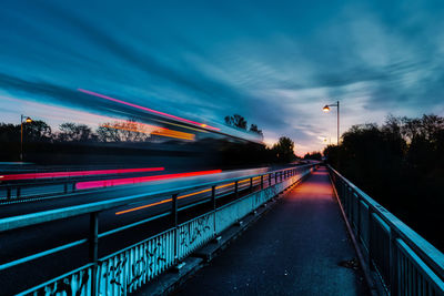 Blurred motion train against sky at dusk