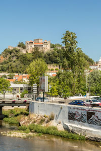 Houses by river in town against clear blue sky