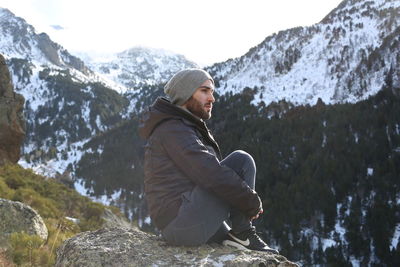 Man sitting on rock against mountain