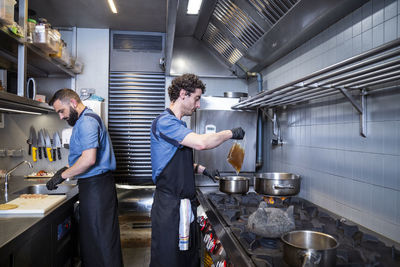 Side view of male chefs preparing food in commercial kitchen