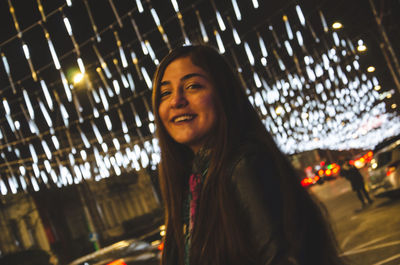 Portrait of smiling young woman standing at night