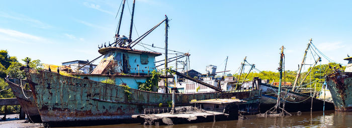 View of abandoned fishing boats moored at pier against sky