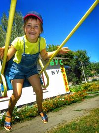 Portrait of happy girl swinging at playground