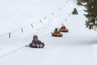 People tobogganing on snowy land