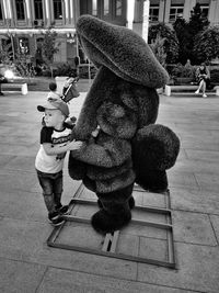Rear view of woman with toy standing against graffiti