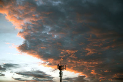 Low angle view of tower against dramatic sky during sunset