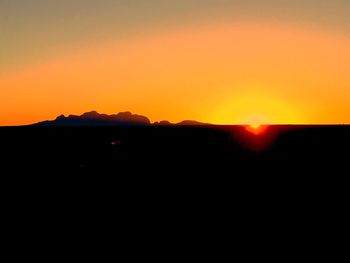 Scenic view of silhouette mountains against orange sky