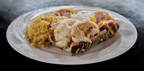 Baked lobster tail with yellow rice and vegetables.