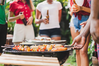 Midsection of people enjoying by barbecue grill