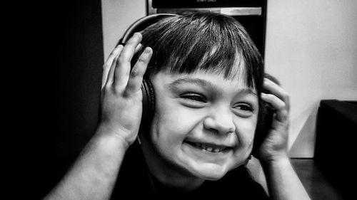 Close-up of smiling boy listening music at home