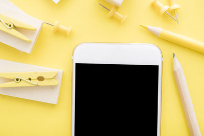 Directly above shot of office supplies on yellow background