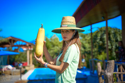 Side view of young woman wearing hat against blue sky