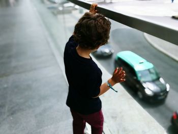 High angle view of boy looking through glass at footbridge