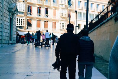 Rear view of people walking on street in city