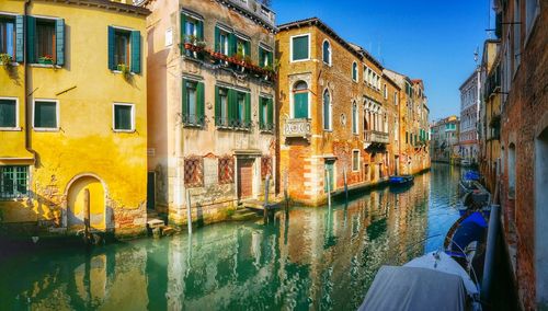 Boats moored on canal amidst buildings