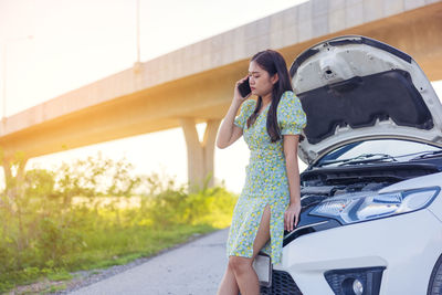 Young woman using mobile phone on road