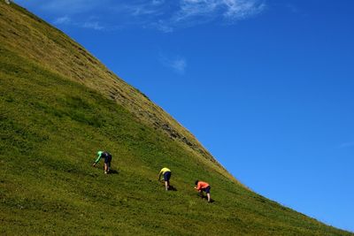 People walking on field against blue sky