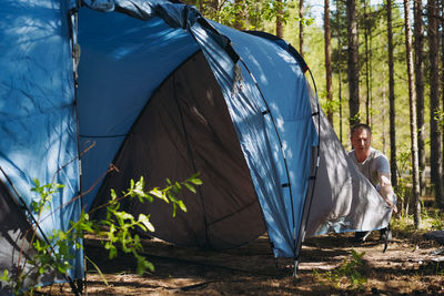 Caucasian man wearing a hat putting up a tent. family camping concept
