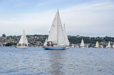 Sailboats sailing on sea against sky