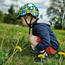 Boy in a bicycle helmet blowing on a dandelion