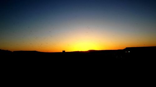 Silhouette landscape against clear sky during sunset