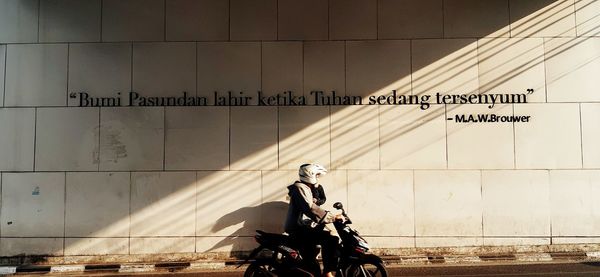 Man riding bicycle against wall