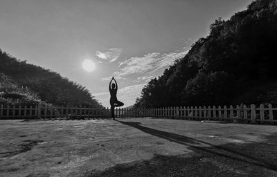 Rear view of woman exercising while standing by railing against mountains and sky