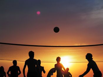 Group of silhouette people playing volleyball at sunset