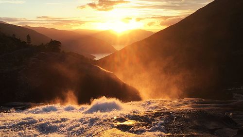 Scenic view of waterfall against sky during sunset