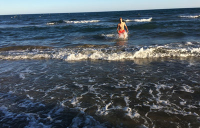 Shirtless man walking at beach