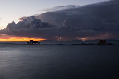 Scenic view of sea against dramatic sky during sunset