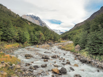 Scenic view of river by mountains against sky