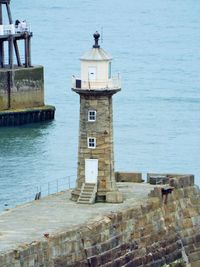 Lighthouse by sea against building