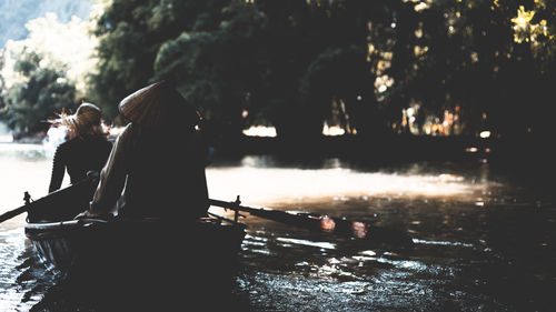 Rear view of man and woman on boat sailing in river