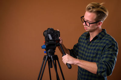 Man photographing with camera against brown background