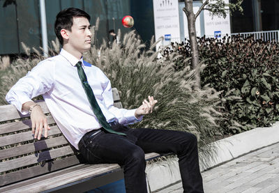 Businessman tossing apple while sitting on bench