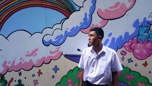 Full length of man standing against graffiti wall
