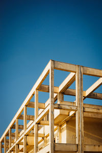 Low angle view of ladder by building against clear blue sky