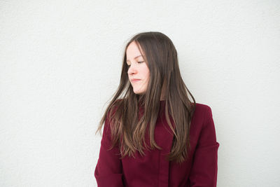 Mid adult woman looking away while standing against wall