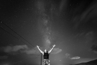 Rear view of man standing on road at night