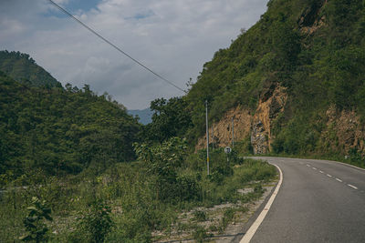 Road by trees against sky