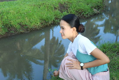 Side view of young woman sitting on field