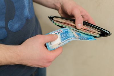 Midsection of man removing paper currency from wallet