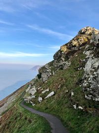 Scenic view of sea by mountain against sky