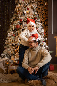 Portrait of smiling girl sitting on christmas tree