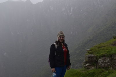 Portrait of woman standing on mountain in foggy weather