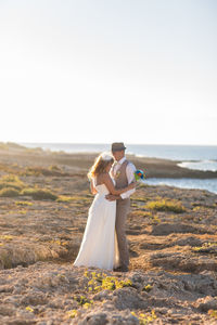 Rear view of woman with umbrella on sea shore against sky